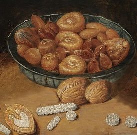 A bowl containing dried figs, candied fruit and nuts, with sweets made from white sugar lying on the table.