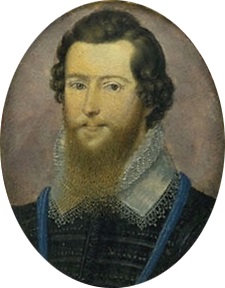 A fair-skinned young man with medium-length dark wavy hair and a light-brown spade-shaped beard.